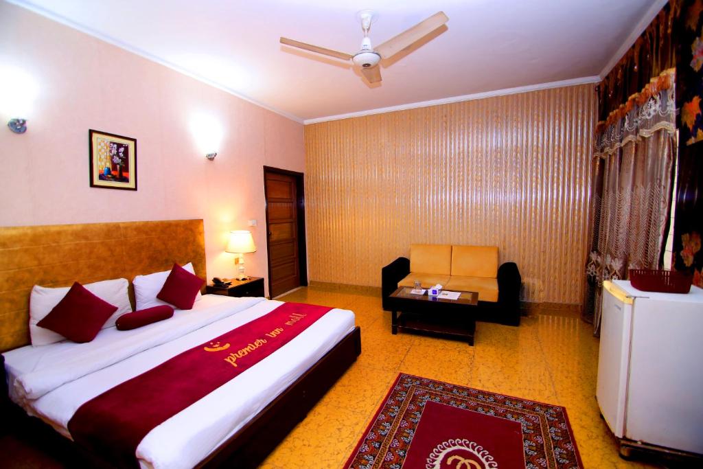 um quarto de hotel com uma cama grande e uma cadeira em Premier inn Mall Lahore em Lahore