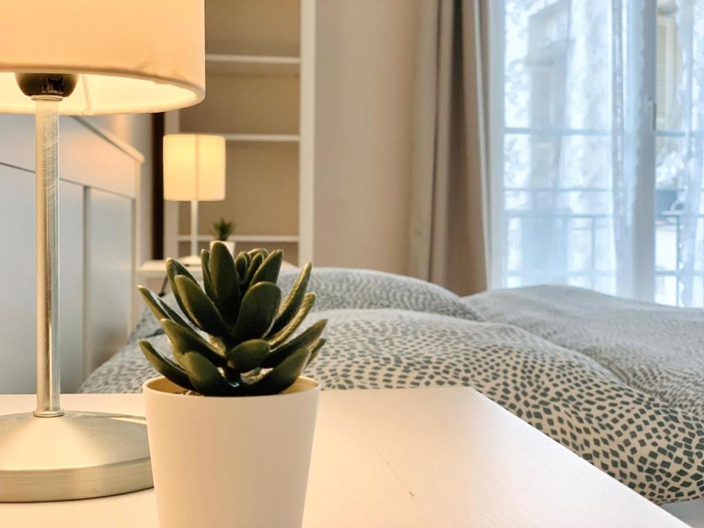 une plante assise sur une table à côté d'un lit dans l'établissement Chic & Spacious Getaway in Nice - 10min to Beach, à Nice
