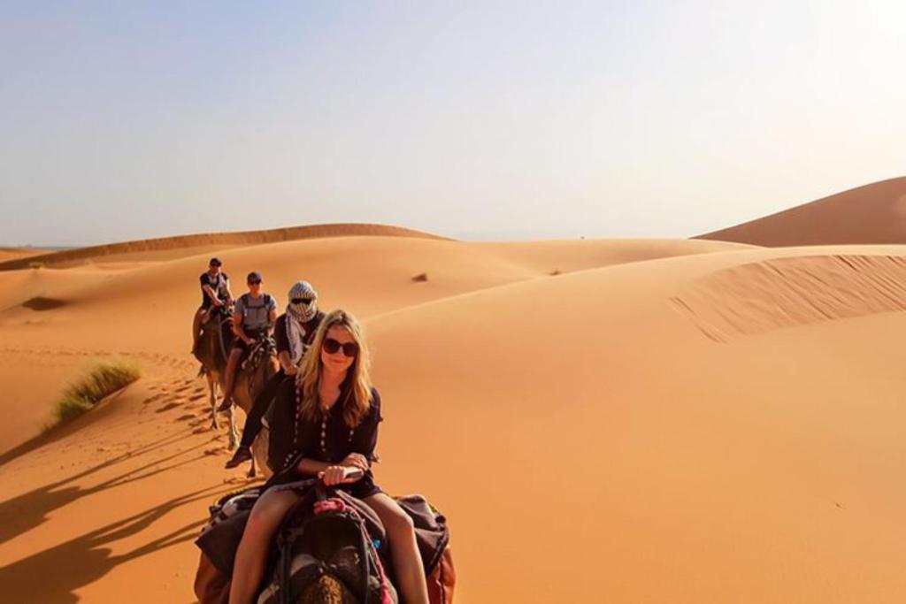 un grupo de gente montando caballos en el desierto en Opulent Sahara Camp, en Merzouga