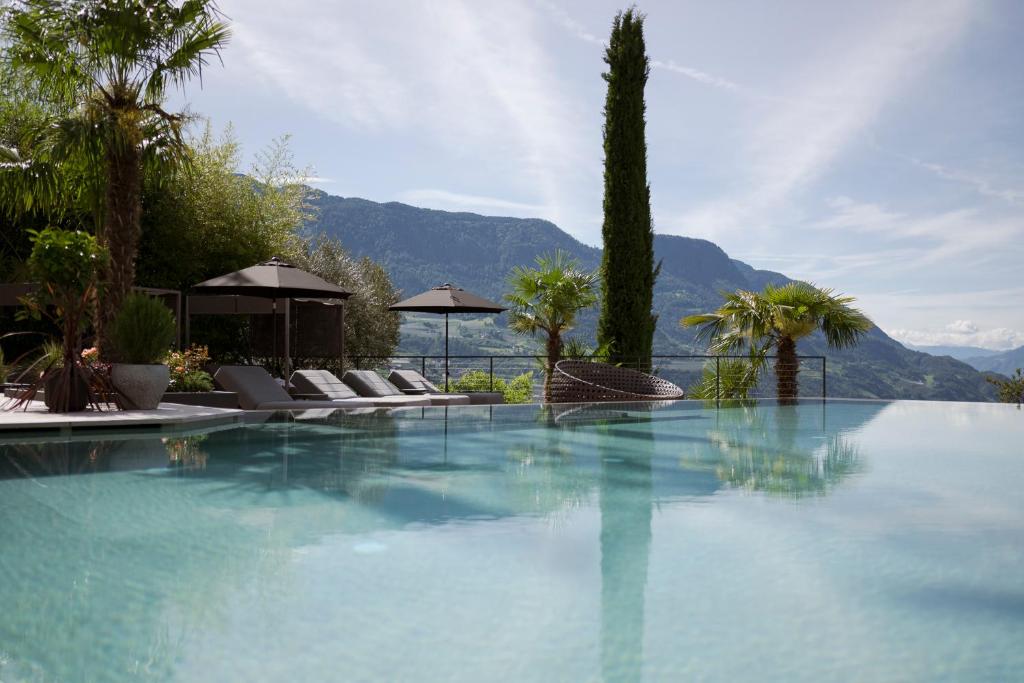 einen Pool mit Stühlen, Bäumen und einem Berg in der Unterkunft Feel good Resort Johannis in Dorf Tirol