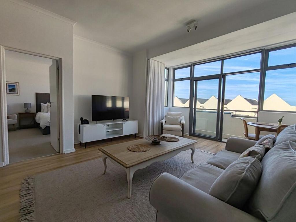 a living room with a couch and a table at Courtside Views Empire Apartment in Muizenberg