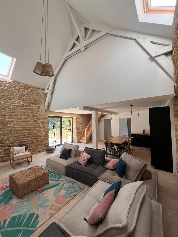 - un grand salon avec un canapé et un mur en briques dans l'établissement La grange - Grande longère à moins de 30 minutes des plages, à Plumelec