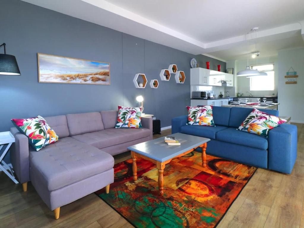 sala de estar con sofá azul y mesa en Sea Life Muizenberg, en Muizenberg