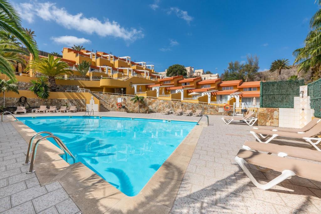 a pool at a resort with chairs and condos at Apartamentos Punta Marina by LIVVO in Morro del Jable