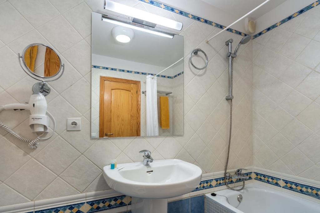 a bathroom with a sink and a mirror and a tub at Apartamentos Punta Marina by LIVVO in Morro del Jable