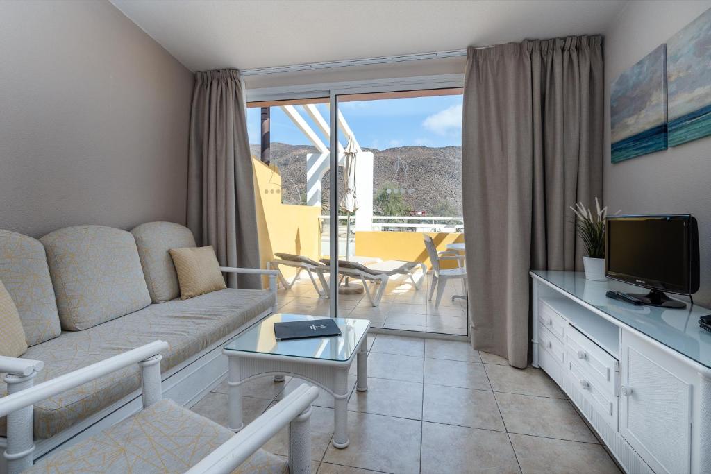 a living room with a couch and a tv at Apartamentos Punta Marina by LIVVO in Morro del Jable