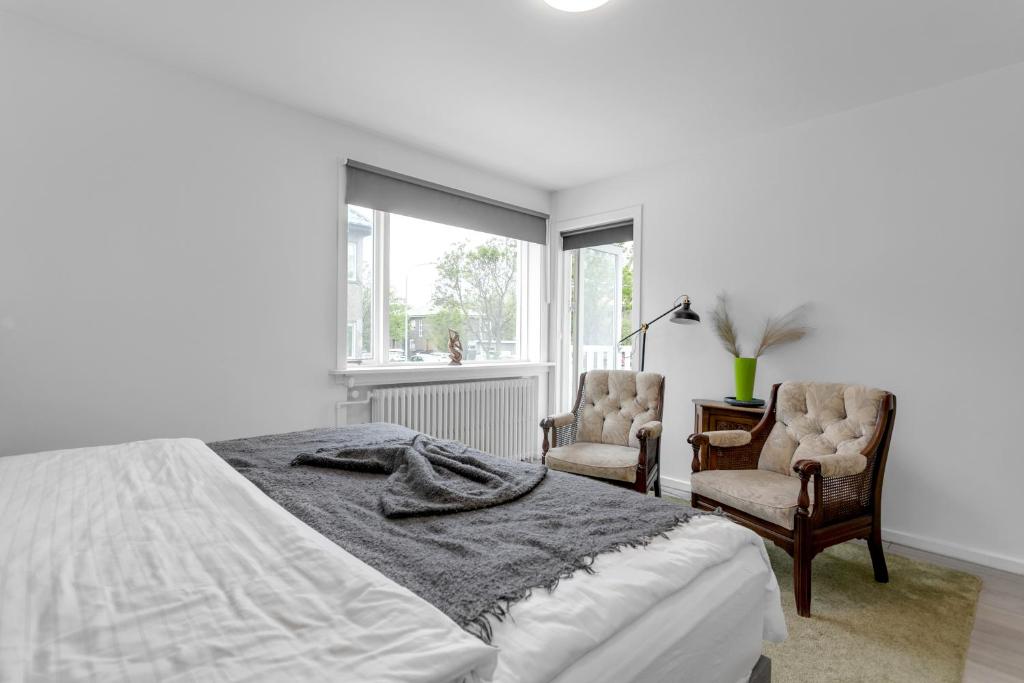 een witte slaapkamer met een bed en 2 stoelen bij Flóki by Guesthouse Reykjavík in Reykjavík