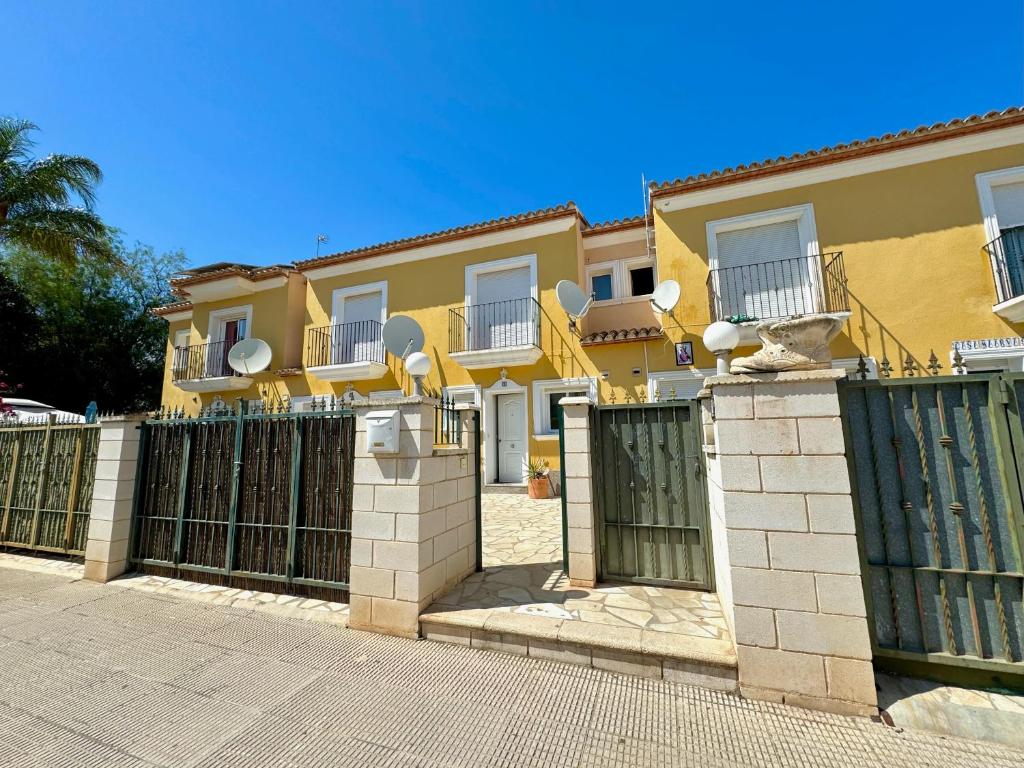 a yellow house with a gate and a fence at Adosado Ausias March in Els Poblets