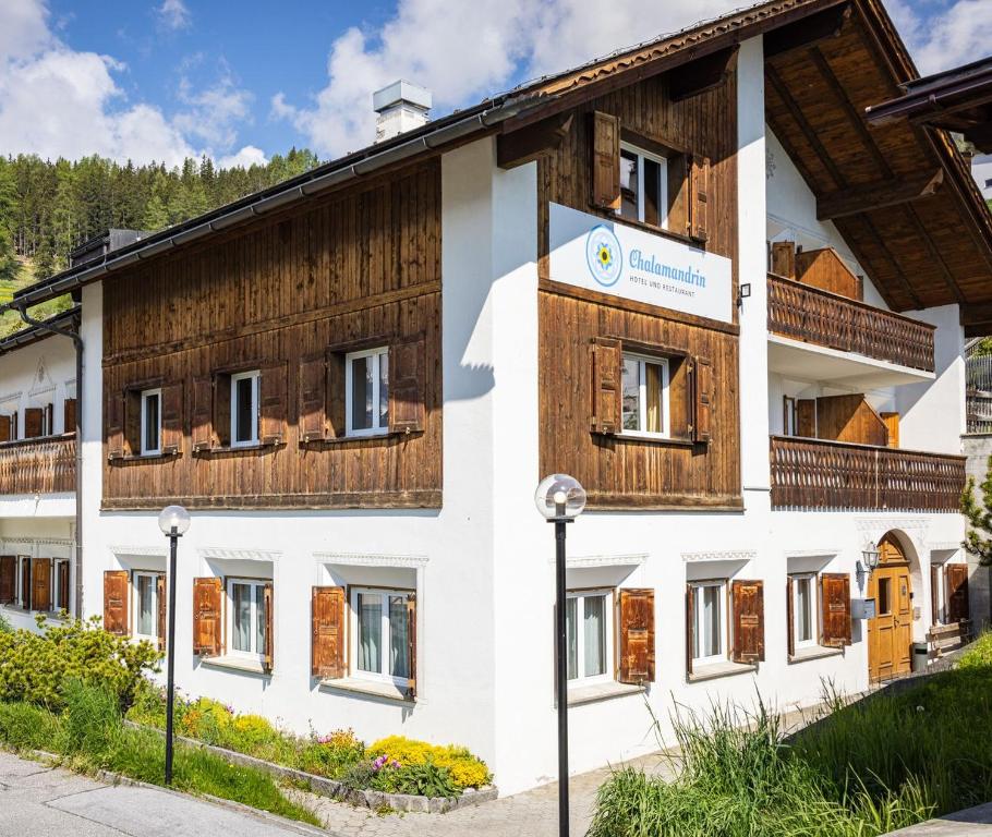 a large white building with wooden accents at Hotel Chalamandrin in Ftan