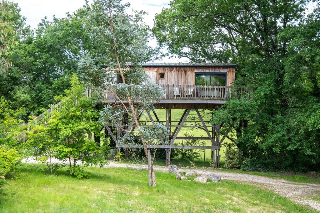 a tree house with a deck in the trees at La cabane de Gardelac in Saint-Rémy