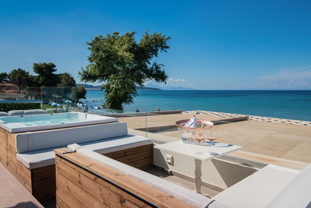 a balcony with a tub and a table and the ocean at Kavo Seaside Luxury Apartment in Argasi