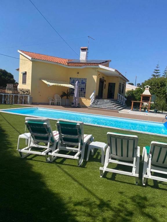 a group of lawn chairs next to a swimming pool at Cotovia Lodge in Sesimbra