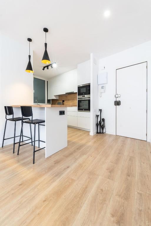 Hotel Apartamento Granollers, an open kitchen and dining room with white walls and wood floors at Apartamento Granollers in Granollers