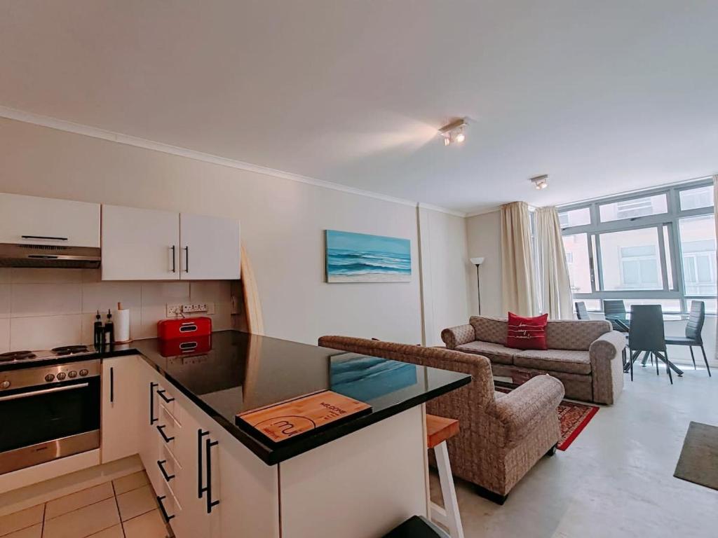 a kitchen and a living room with a couch at Oceans Place Empire Apartment in Muizenberg