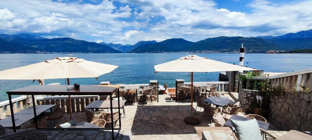 a patio with tables and umbrellas next to the water at Luxury Sea Residence by Kristina in Tivat