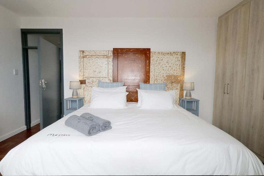 Una cama blanca con una toalla encima. en South Surf Apartment, en Muizenberg