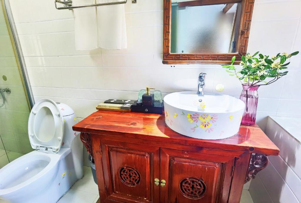 a bathroom with a sink and a toilet and a mirror at 原乡文苑客栈 in Lijiang