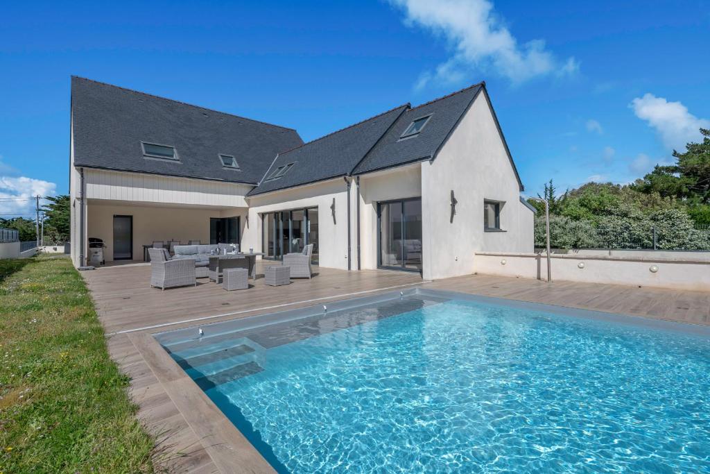 a house with a swimming pool in front of a house at Piscine - 10 personnes - 100m de la plage in Saint-Sébastien