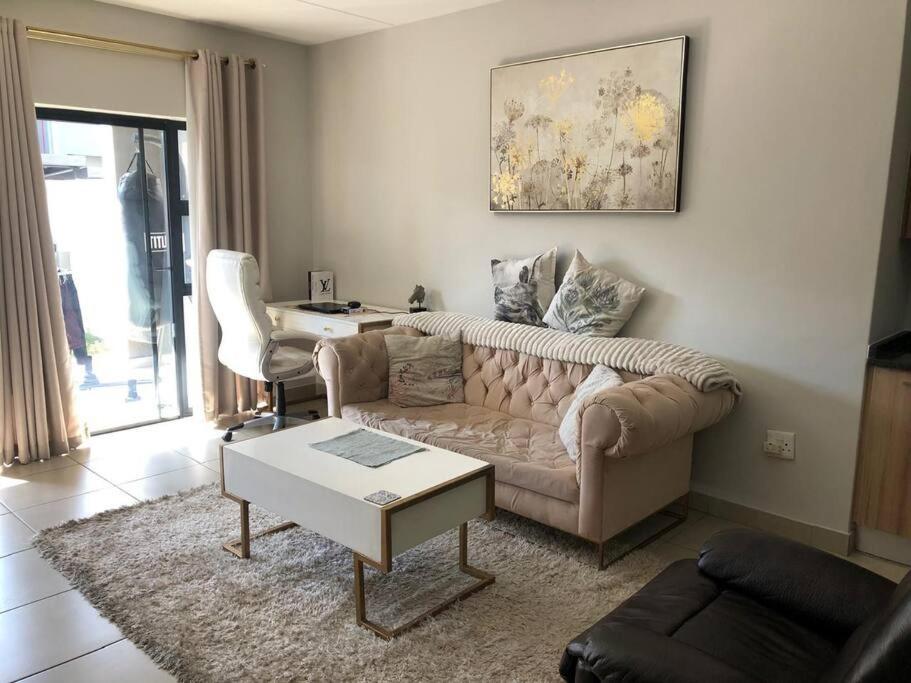 una sala de estar con un sofá y una mesa en Exquisite Home In Sandton with Pool and Inverter, en Johannesburgo