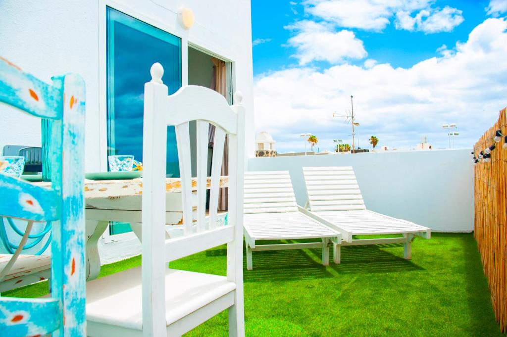 Cette chambre dispose d'un balcon avec un lit et des chaises. dans l'établissement Callao beachhouse, à Playa Honda