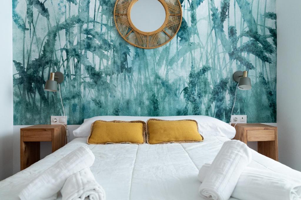 - une chambre avec un lit et un miroir mural dans l'établissement Apartamento del Mercado, à Cadix