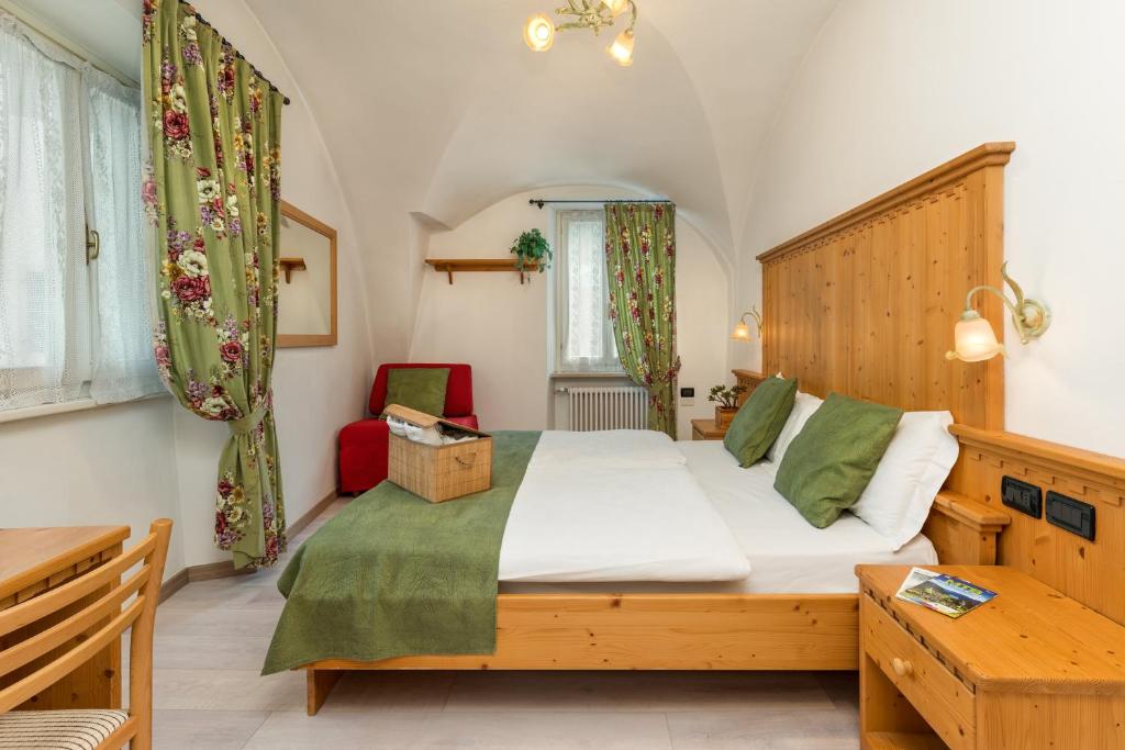 Schlafzimmer mit einem großen Bett mit einem Kopfteil aus Holz in der Unterkunft Albergo Alla Costa in Ledro