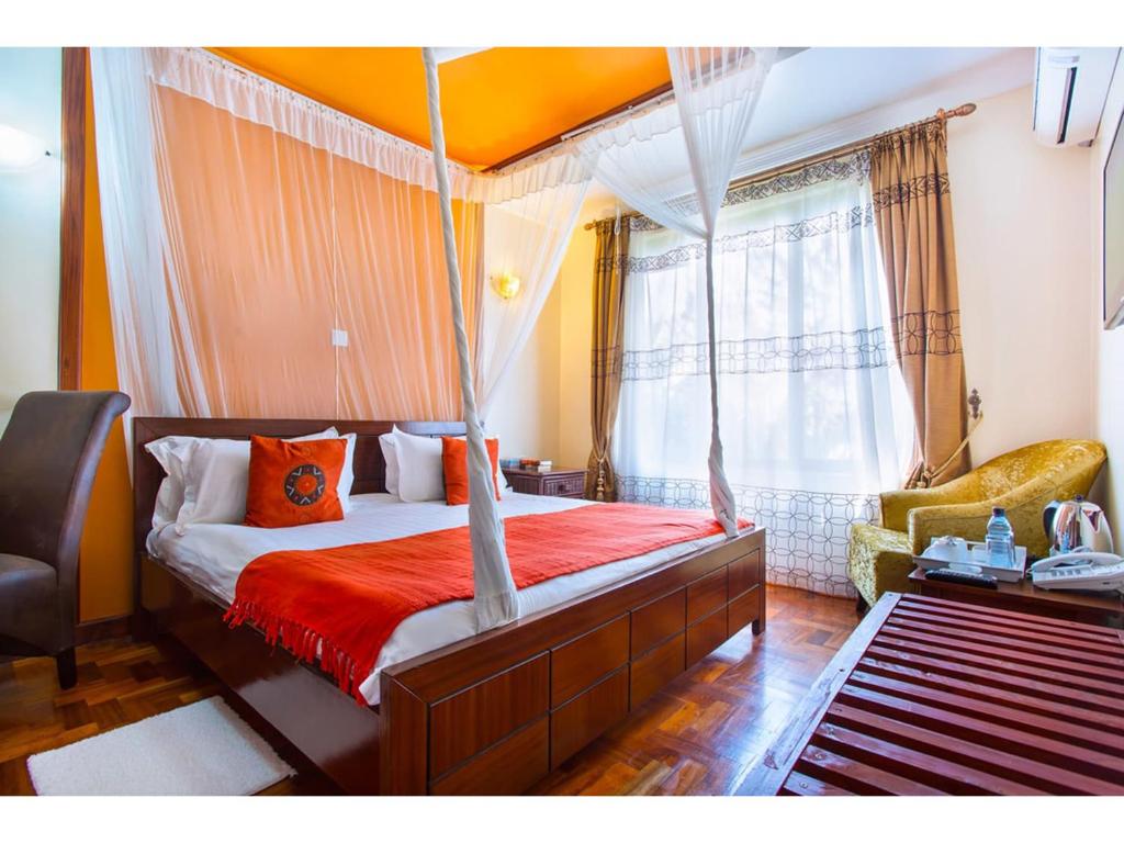 sypialnia z łóżkiem z baldachimem i krzesłem w obiekcie Wigot Gardens Hotel w mieście Kisumu