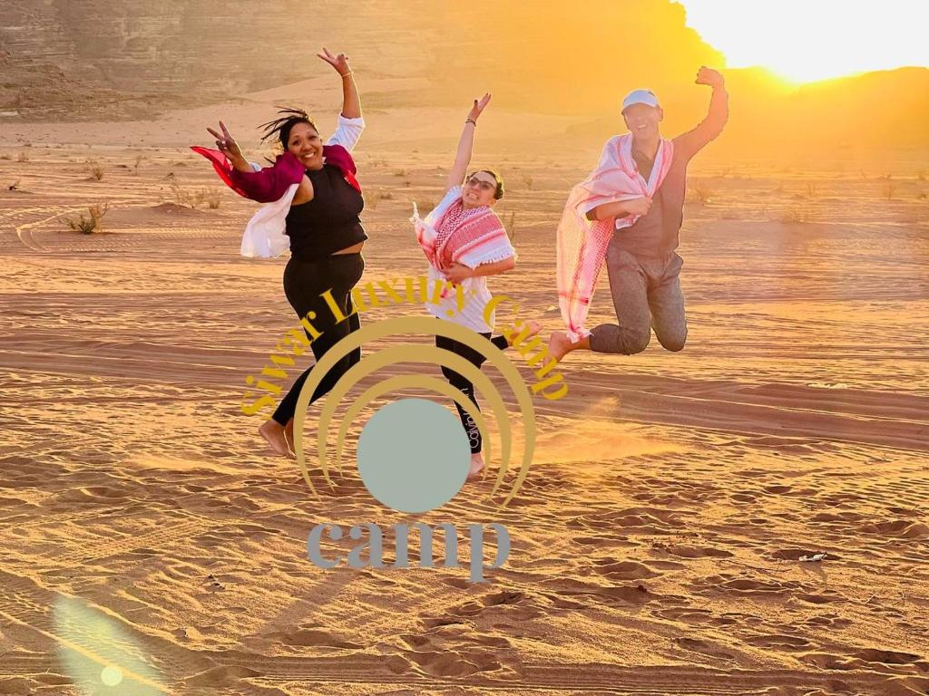 a group of people jumping in the sand on the beach at Siwar Luxury Camp in Wadi Rum