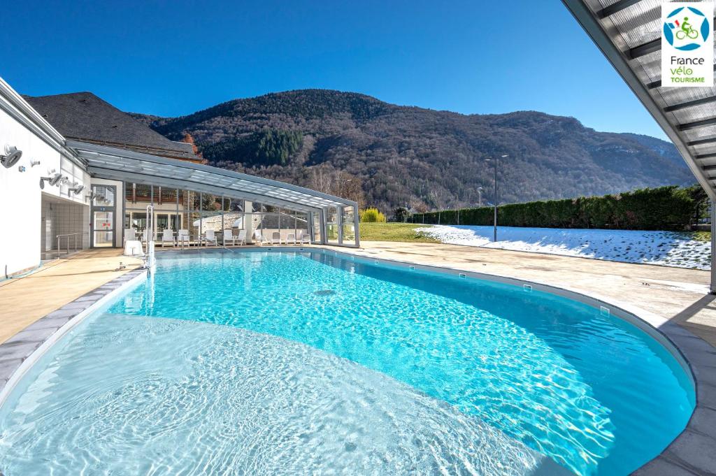 une grande piscine bleue avec une montagne en arrière-plan dans l'établissement Village Club Les Balcons des Pyrénées, à Saint-Mamet