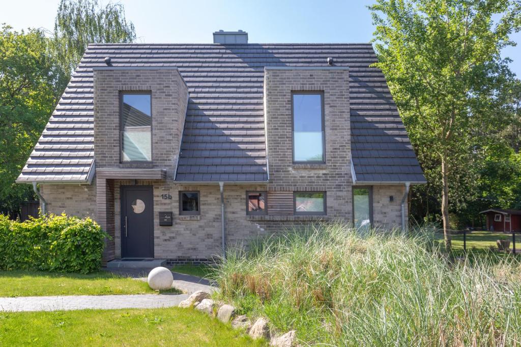 une maison en briques avec un toit noir dans l'établissement Hus Veer, à Sankt Peter-Ording