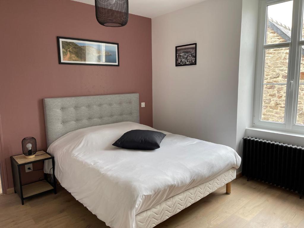 a bedroom with a bed with a black pillow on it at La petite Irlande in Auderville