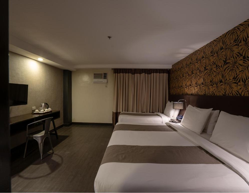 Pokój z 3 łóżkami i biurkiem w obiekcie GT Hotel Jaro w mieście Iloilo