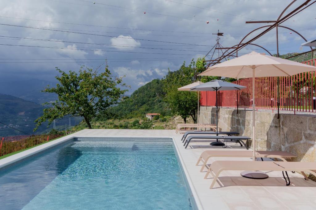 a pool with chairs and umbrellas on a building at Feel Discovery Villa Aura Douro Valley in São Martinho de Mouros