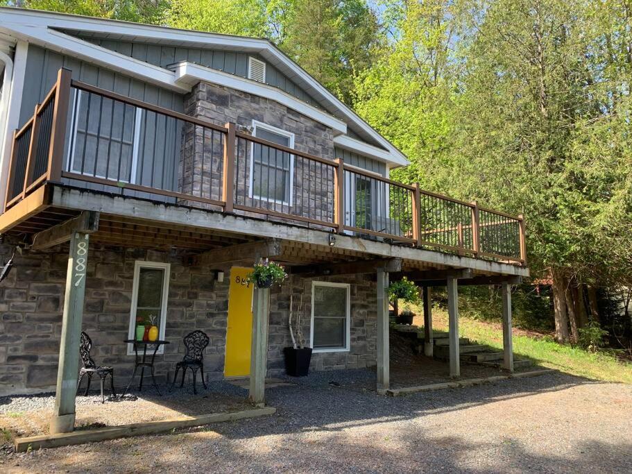 a house with a deck and a table and chairs at Chalet Émond - Petit Train du Nord, Golf et ski in Mont-Tremblant