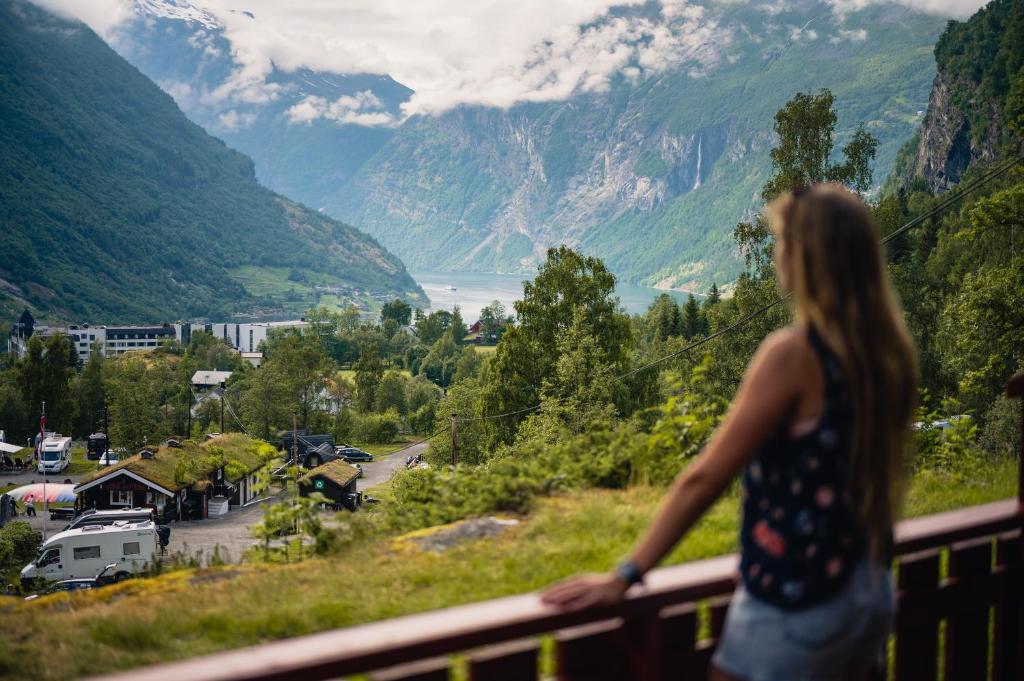 a woman standing on a balcony looking at a valley at Vinje Camping in Geiranger