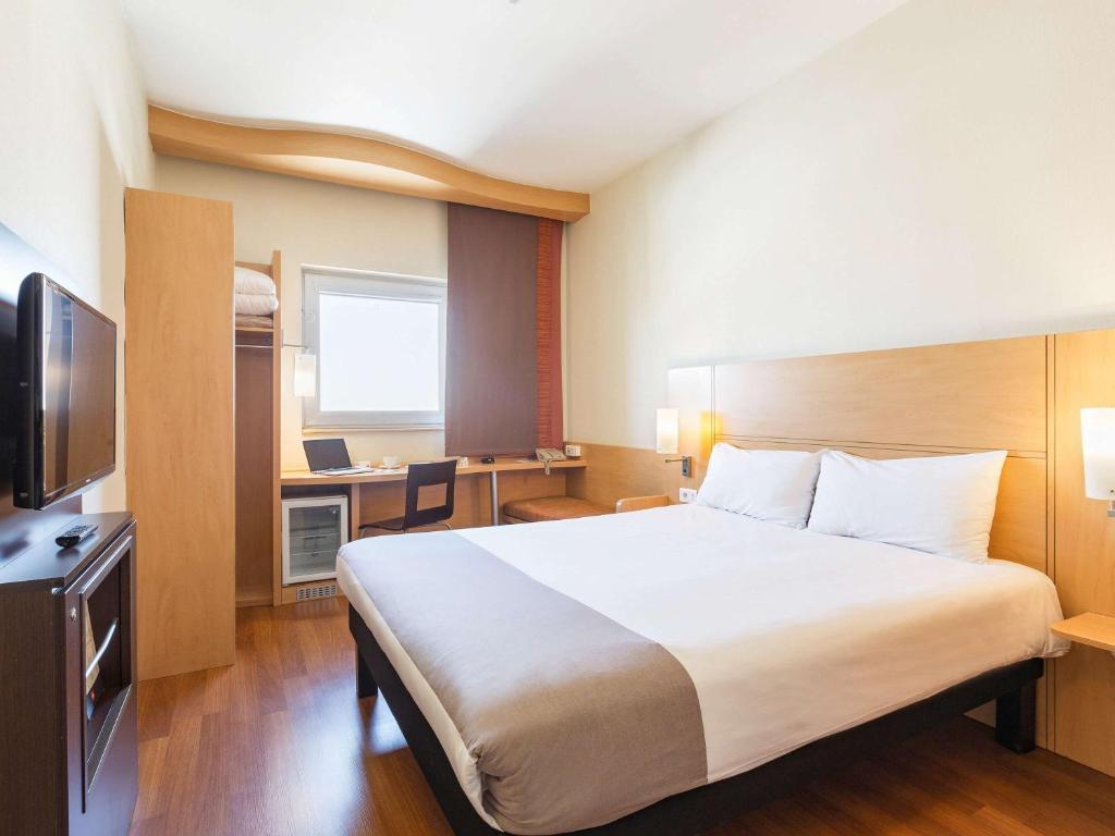 a hotel room with a large bed and a desk at Ibis Gaziantep in Gaziantep