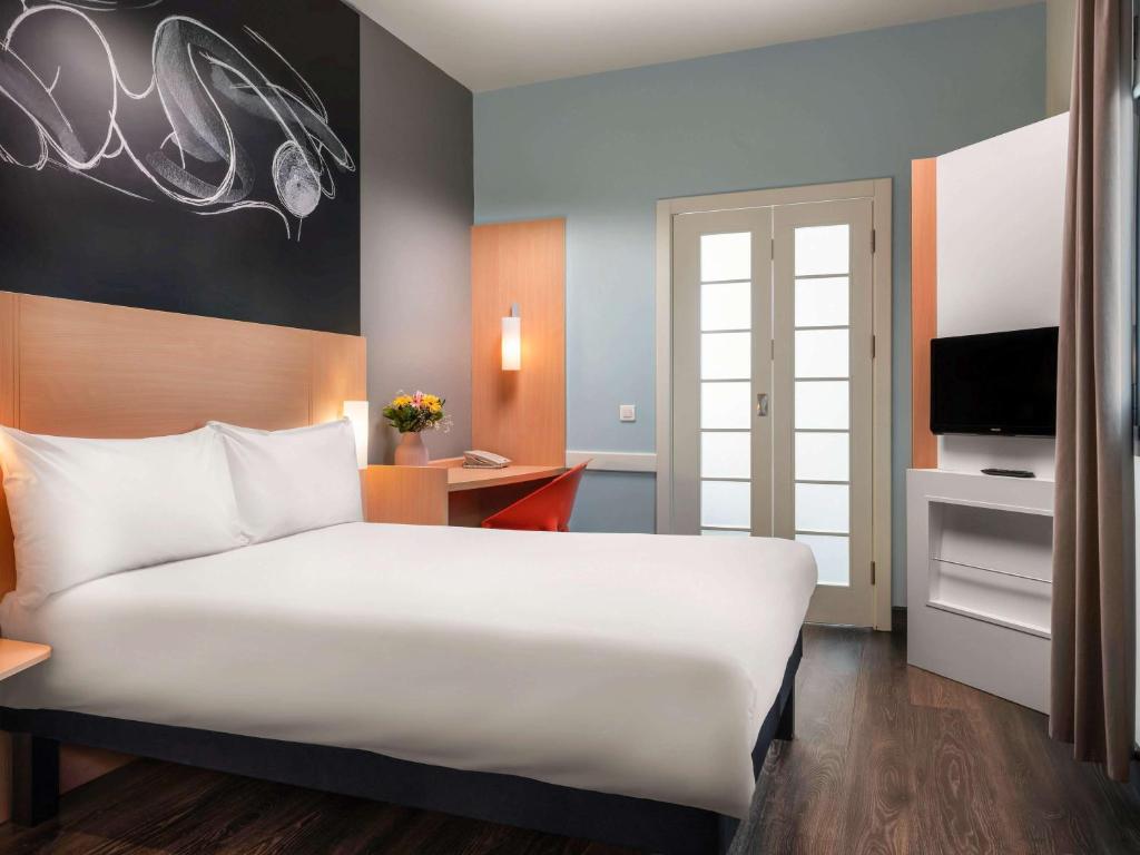 فندق ibis Ankara Airport في أنقرة: غرفة نوم مع سرير أبيض كبير ومكتب