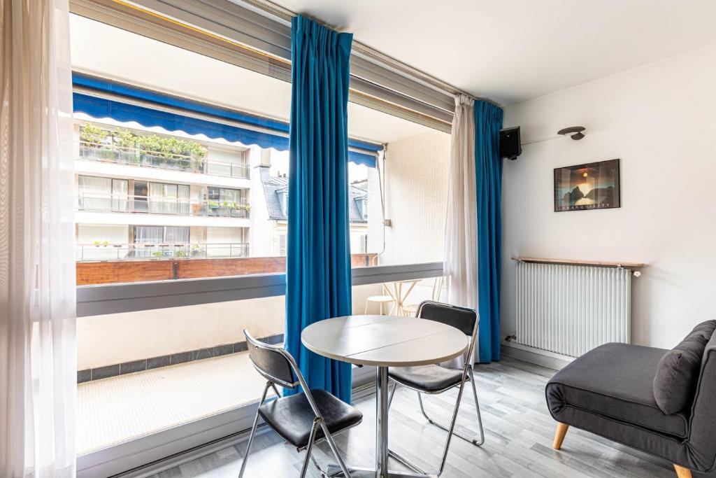 un salon avec une table et des chaises et une fenêtre dans l'établissement GuestReady - One perfect studio in Auteuil, à Paris
