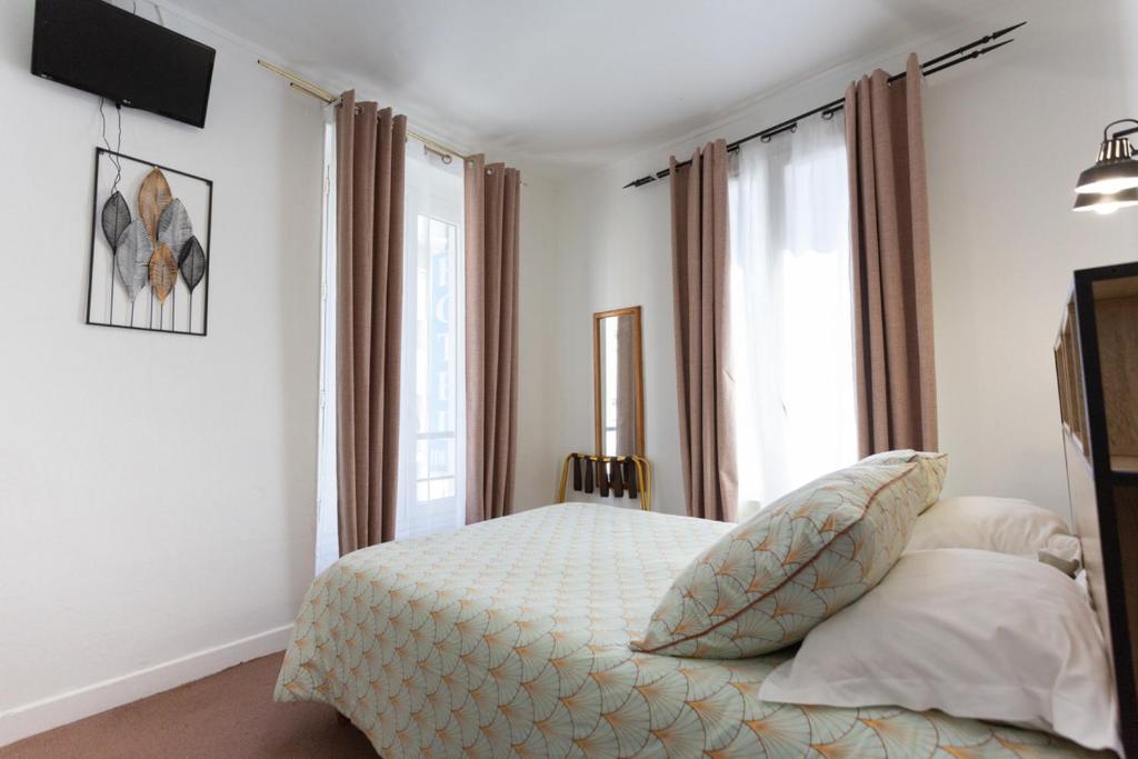 um quarto com uma cama e uma grande janela em Ideal Hotel em Paris