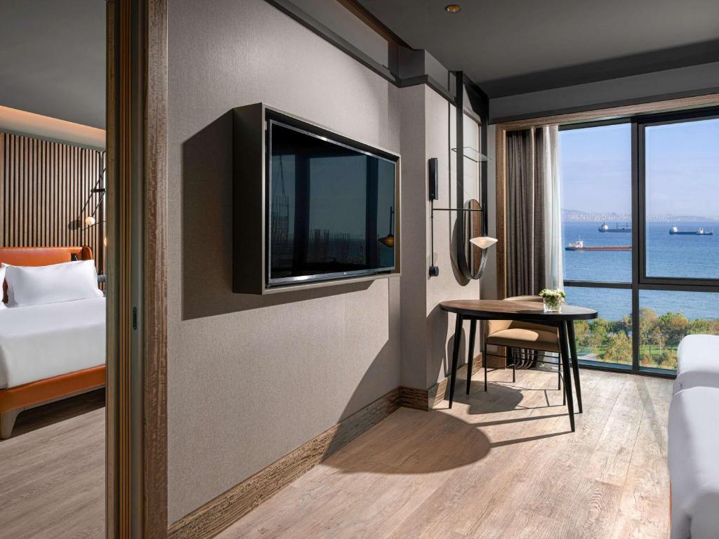 een kamer met een bed en een tafel met een televisie bij Mövenpick Hotel Istanbul Marmara Sea in Istanbul