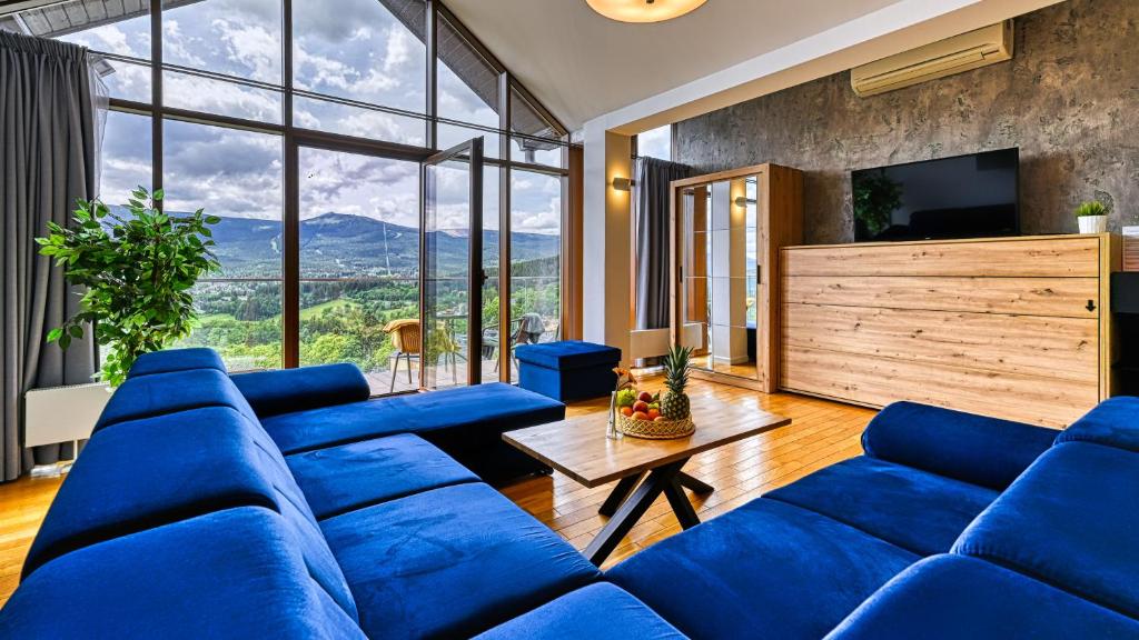 a living room with blue couches and a large window at Apartamenty Sun & Snow Resorts in Szklarska Poręba