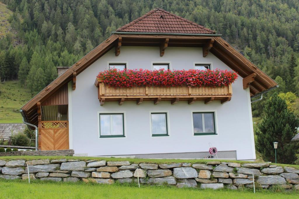 ein Haus mit einem Balkon mit roten Blumen darauf in der Unterkunft Gästehaus Maria Trattner in Mauterndorf