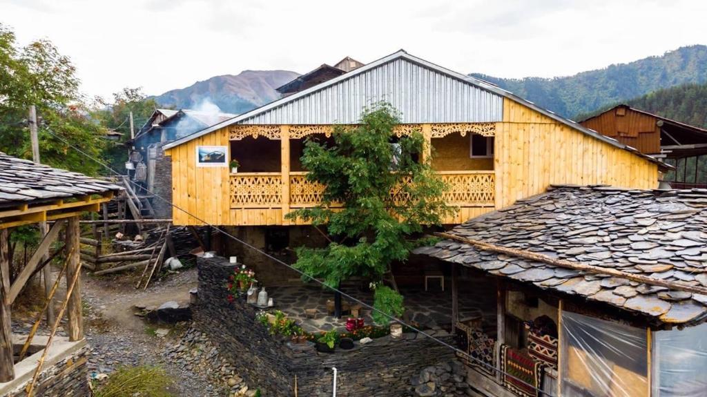 a wooden house with a balcony in a village at Above the Clouds in Tusheti