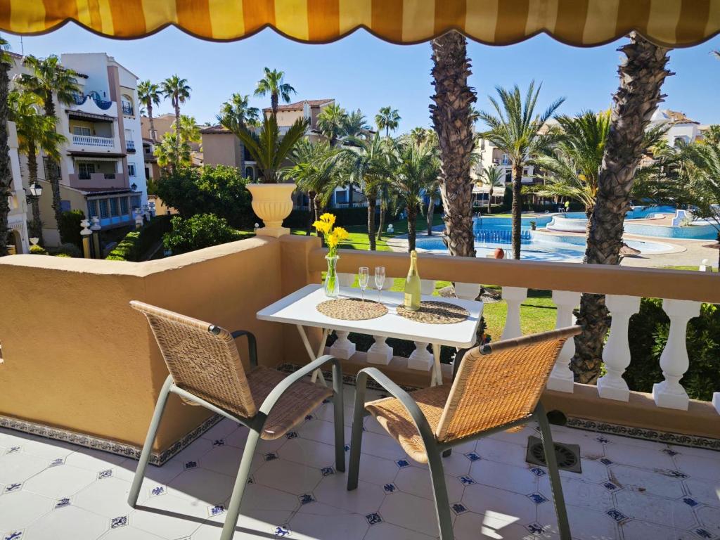 a table and chairs on a balcony with palm trees at Aldea de Meer in Torrevieja