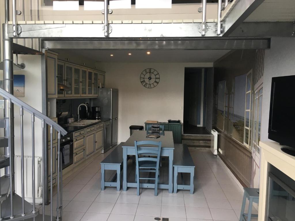 a kitchen with a table and chairs and a clock on the wall at L'Entre Vagues in Saint-Jean-de-Monts