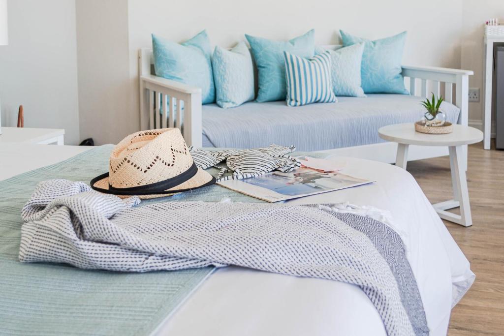 un sombrero y una manta en una cama con sofá en Bayview Hotel, en Plettenberg Bay