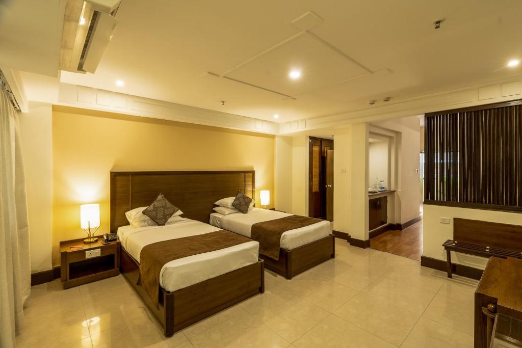een hotelkamer met 2 bedden en een televisie bij Ivory Tower in Bangalore