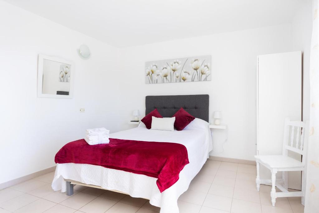 a white bedroom with a large white bed with a red blanket at Home2Book Comfy Studio Frontera in Frontera
