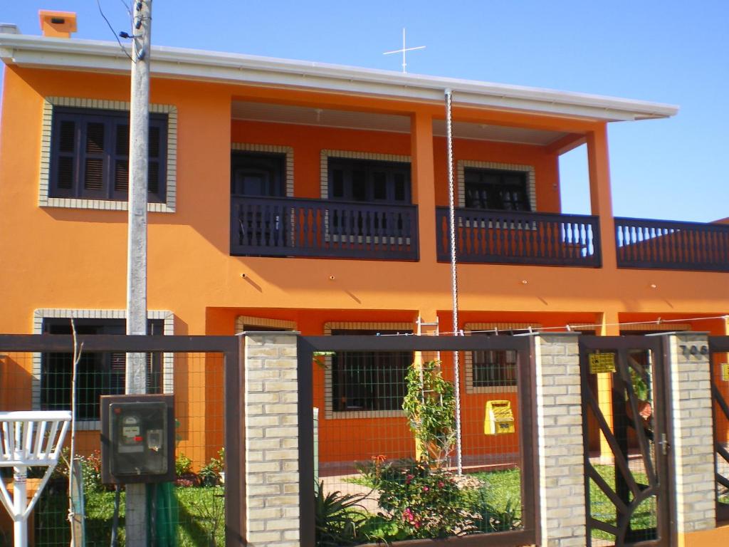 an orange house with a balcony on a street at Casa Oasis Sul Tramandaí in Tramandaí