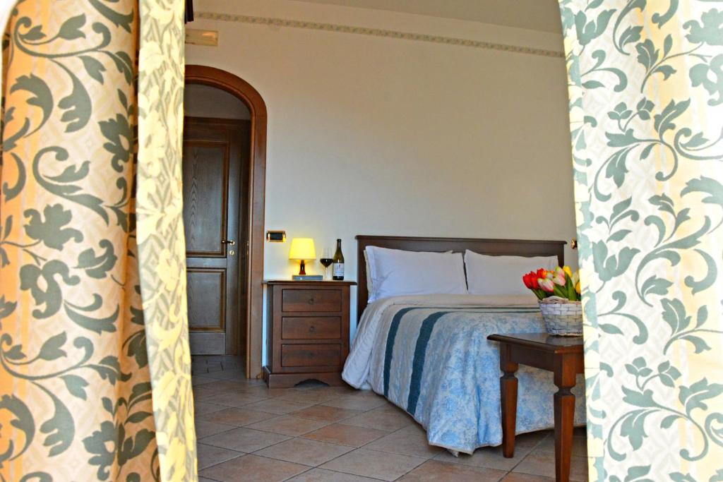 La Locanda del Pettirosso في أَجيرولا: غرفة نوم بسرير وطاولة عليها ورد